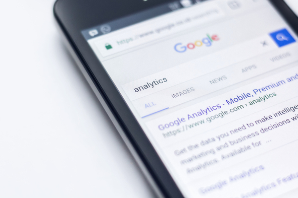 Smartphone exibindo resultados da primeira página da SERP do Google, com o termo de pesquisa “analytics”.