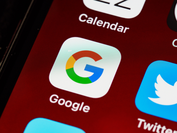A tela de um celular com o plano de fundo vermelho, focando no ícone do Google.