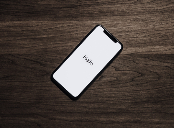 Dispositivo smartphone sobre uma mesa de madeira que traz os dizeres “hello” em sua tela.