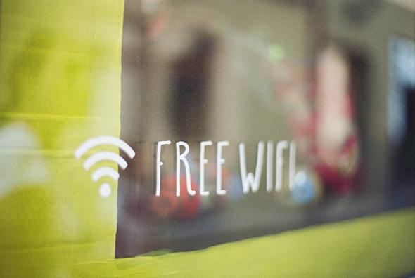 A imagem mostra a vitrine de algum estabelecimento onde é possível ler, em branco, os dizeres “free wifi”, junto ao símbolo da conexão wireless.